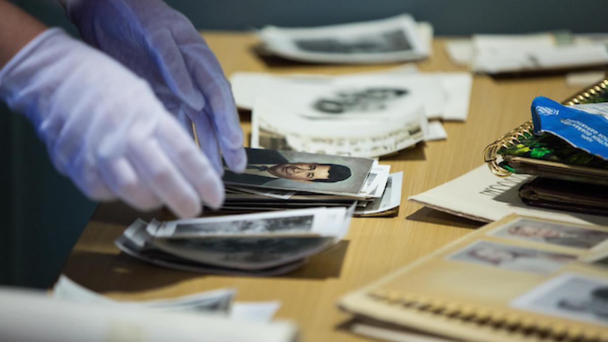 archivist wears gloves while handling photographs to scan and digitize