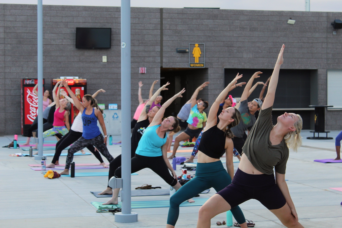 Guests in workout clothes follow instructor doing yoga on the Sun Deck