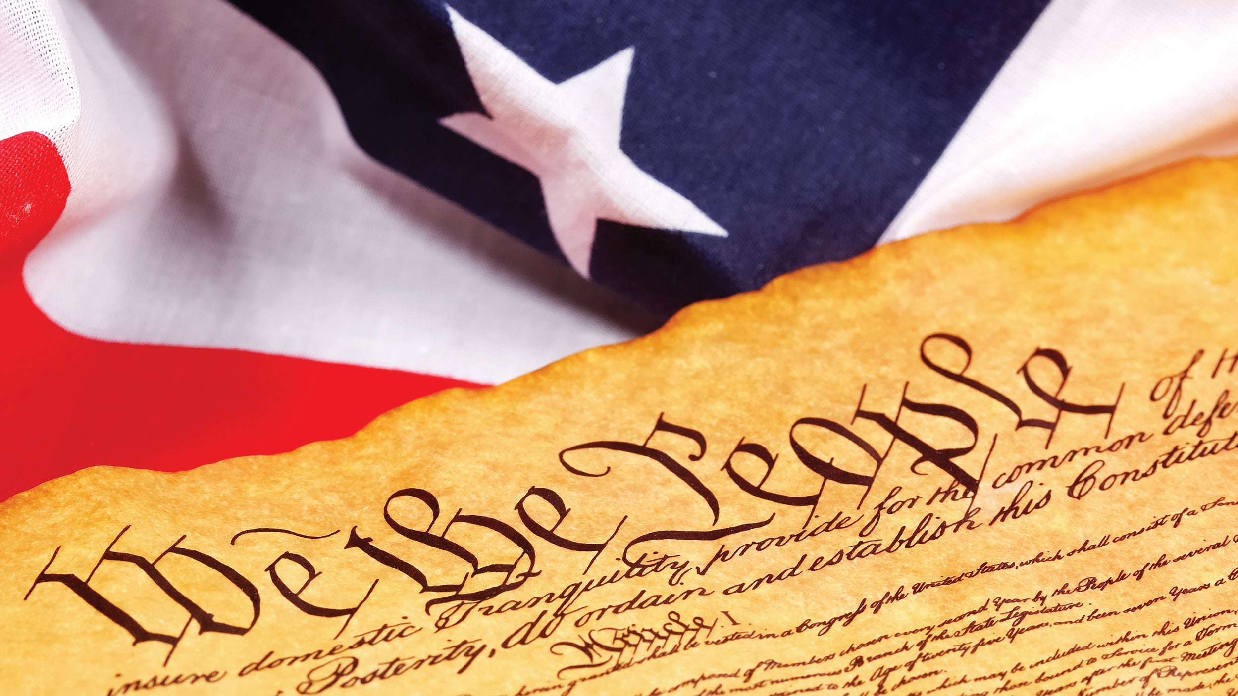 A photograph of the United States flag draped with the United States Constitution