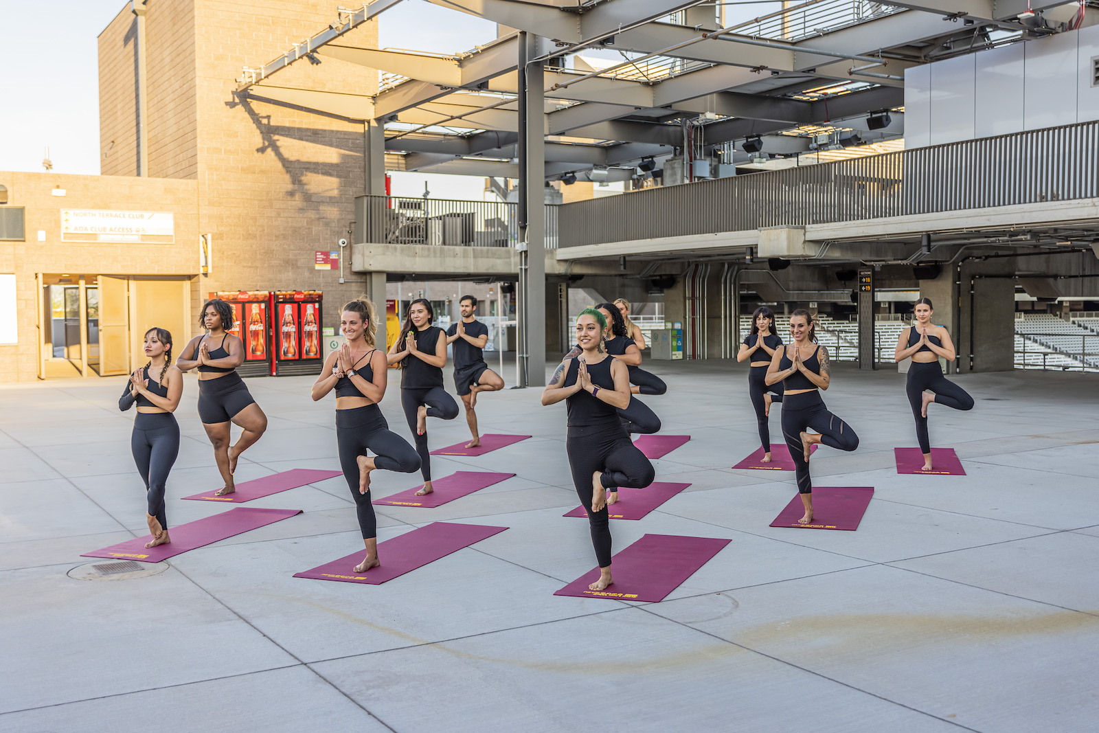 Yoga instructor wearing black fitness outfits gather in tree pose on the Sun Deck.
