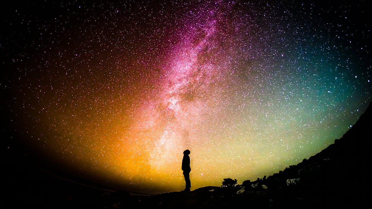 Silhouette of individual standing staring at colorful cosmic night sky