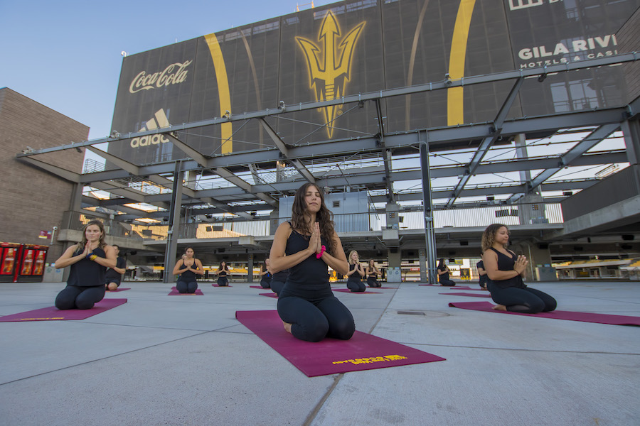 yogs instructors sit on mat with hands to heart outside at ASU 365 Community Union sun deck space at Sunset.