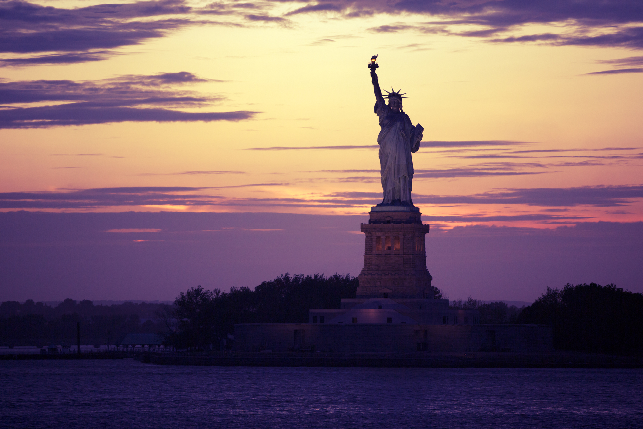 The Statue of Liberty set against a deep purple sunset
