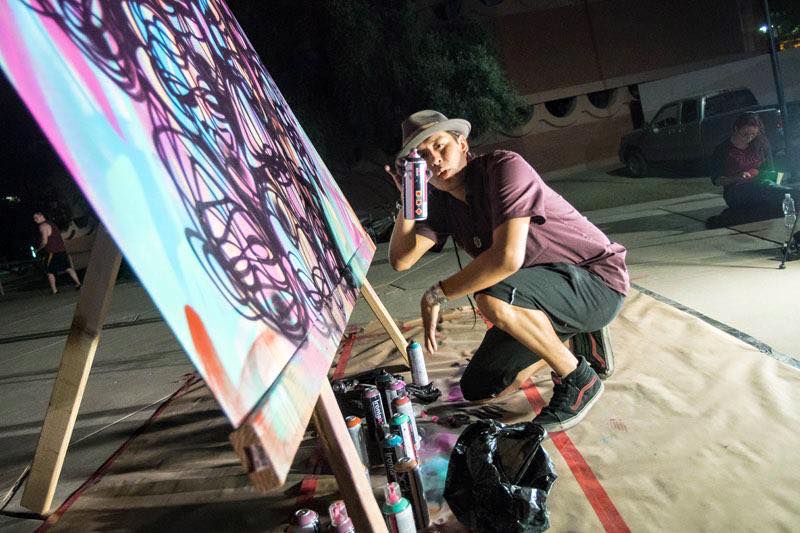 man spray painting graffiti on a canvas