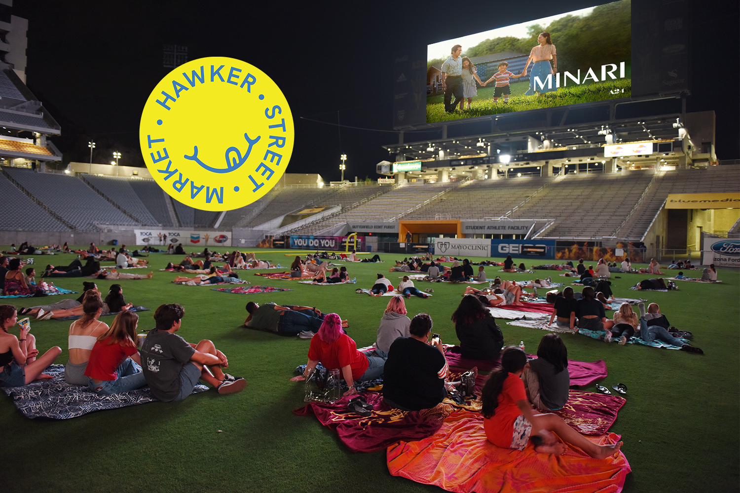 "Minari" plays on the big screen at Sun Devil Stadium. Hawker Street Market logo floats over the image.