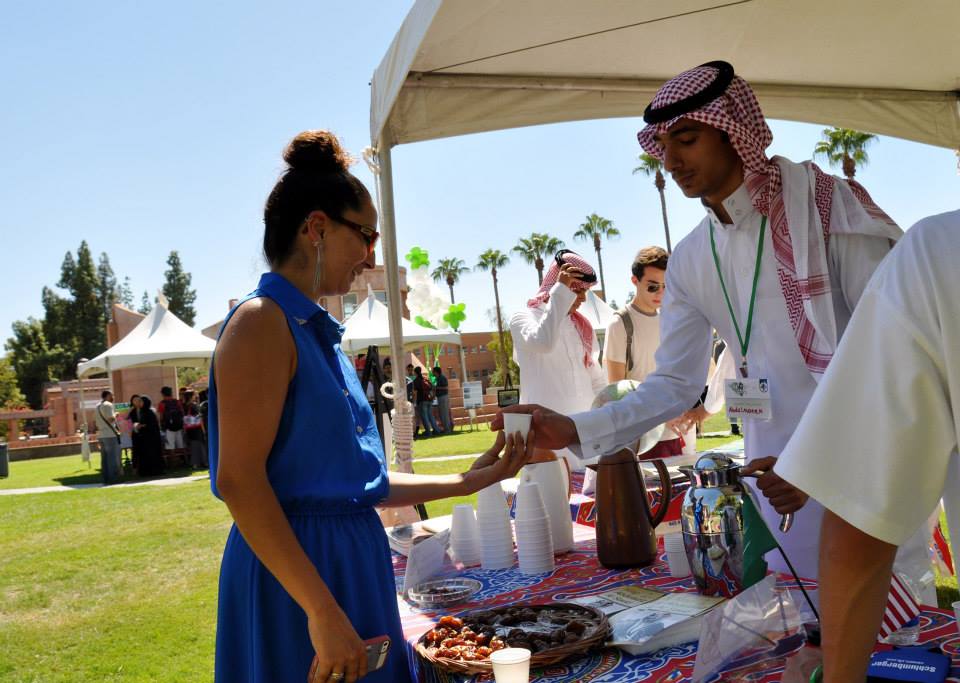 Saudi Arabian student handing food to female student