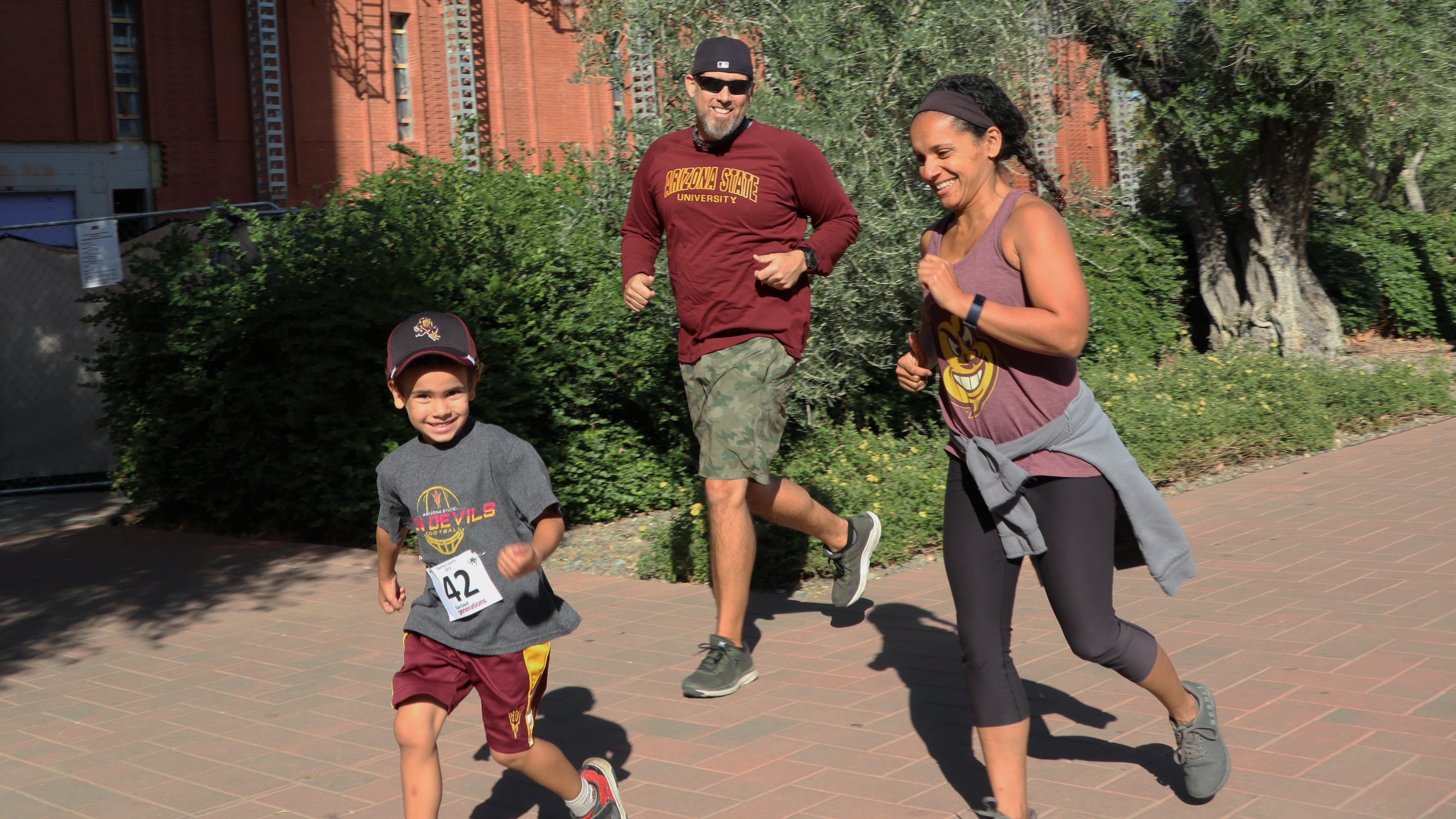 A young future Sun Devil runs with his mom and dad during Sparkys Sprint.