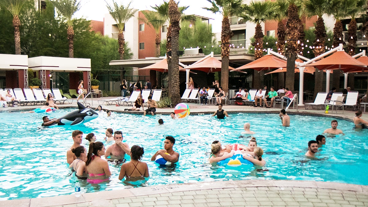 Picture of college students standing in swimming pool using inflated balls and rafts.