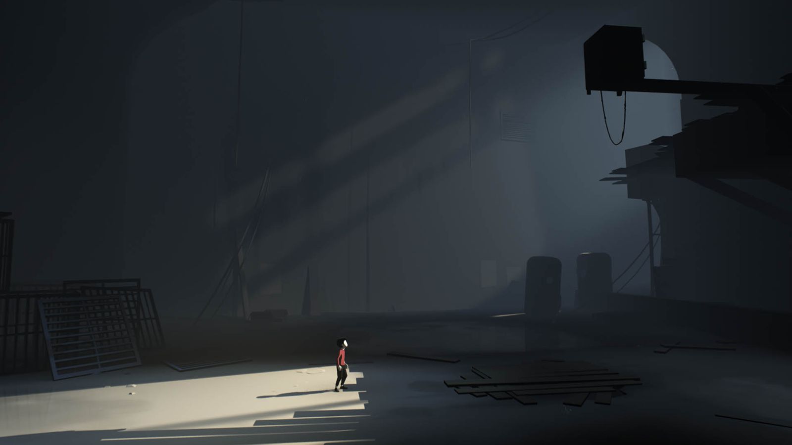 Image from the game Inside. A young boy in a red shirt looks up at a ledge in an industrial environment, upon which is perched a metal safe.