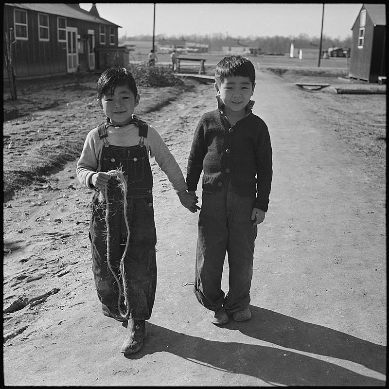Two children walk hand in hand at Jerome, Arkansas Internment camp