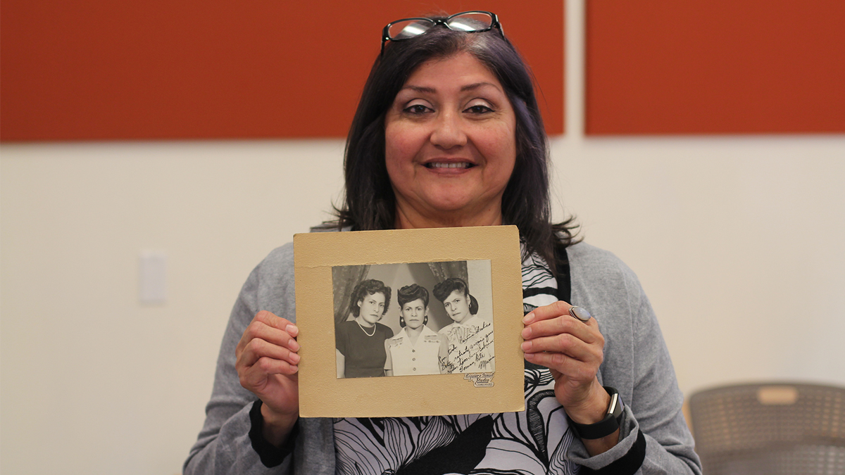 Person smiling and holding a photograph of three people to the camera