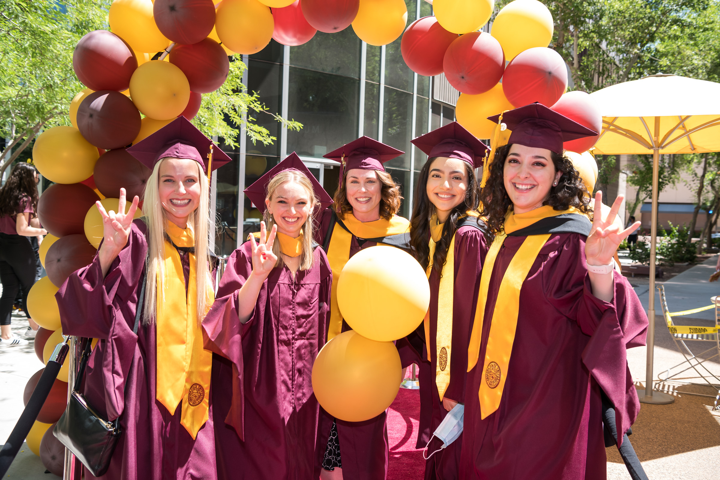 A group of ASU grads smiles in their regalia.