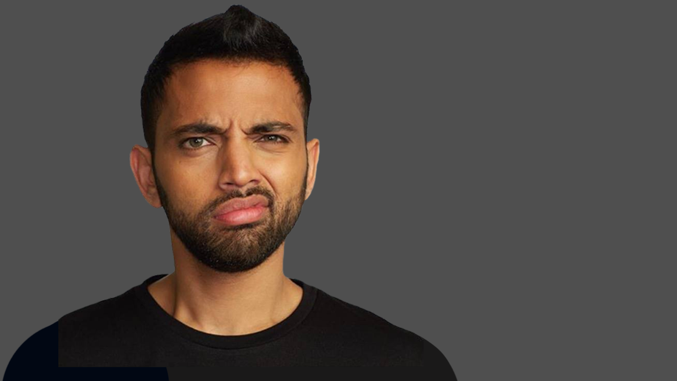 man with annoyed facial expression in black t-shirt in front of gray background