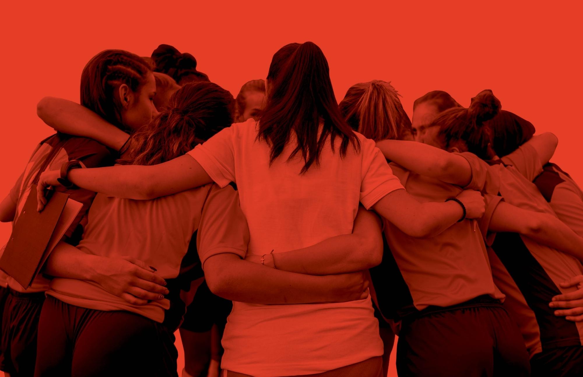 A girls' soccer team huddles up with their backs to the viewer